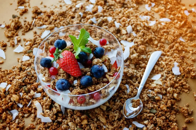 Bol de cereales integrales con frutos rojos y coco sobre fondo de granola.